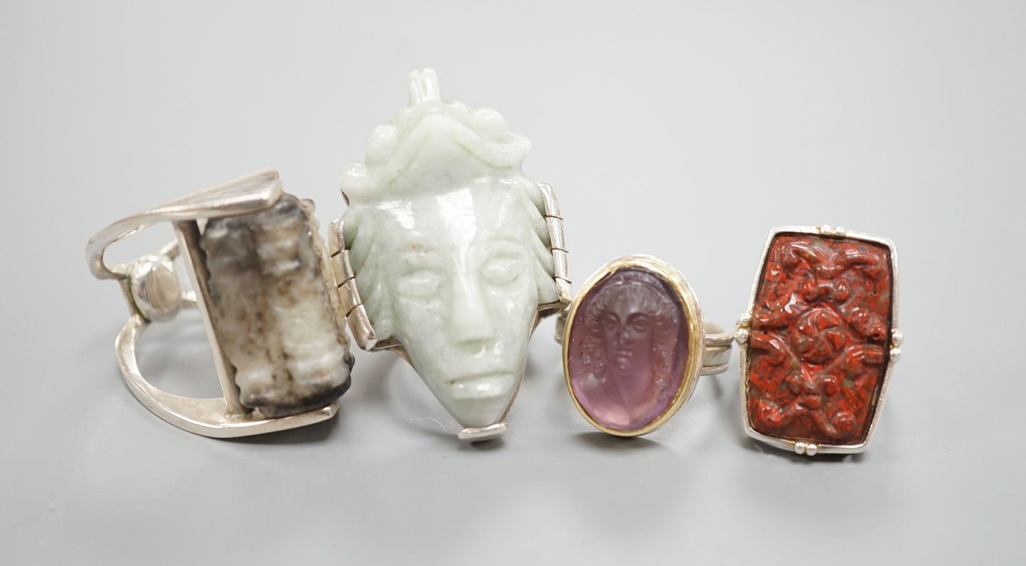 Four white metal mounted jade or hardstone rings